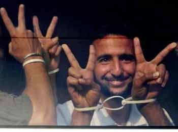 A Palestinian prisoner flashes the v-sign as he is seen on a bus prior to leaving the Ketziot prison near the southern Israeli city of Beersheba, early Thursday, June 2, 2005.
