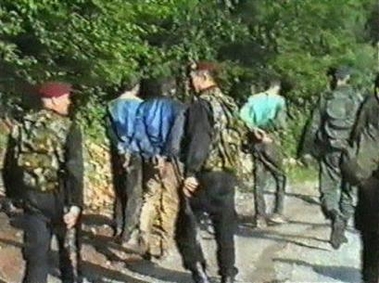 Members of the Serbian police escort prisoners with their hands tied behind their back, in this image from a video introduced by the prosecution during the hearings in the trial of former President Slododan Milosevic at the U.N. court in the Hague, Netherlands, Wednesday June 1, 2005. 