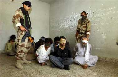 Iraqi army officers stand next to captured men suspected of being militants in Baghdad Saturday June 4, 2005. Iraqi Army's al-Muhtana brigade arrested 19 suspected militants in raids in Baghdad's Abu Ghraib and Sabi al-Bour neighborhoods. (AP 