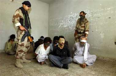 Iraqi army officers stand next to captured men suspected of being militants in Baghdad Saturday June 4, 2005. Iraqi Army's al-Muhtana brigade arrested 19 suspected militants in raids in Baghdad's Abu Ghraib and Sabi al-Bour neighborhoods. (AP