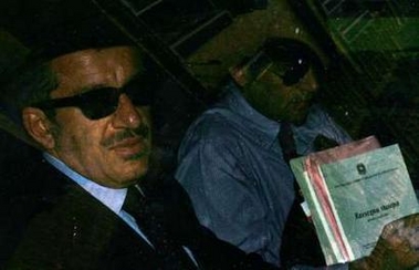 Italian Welfare Minister Roberto Maroni (L) holds a press clipping review as he is seen through a car window leaving his office at Ministry of Labor and Welfare in Rome June 3, 2005. Italy should consider leaving the single currency and reintroducing the lira, Welfare Minister Maroni said in a newspaper interview on June 3, 2005. Maroni is a front-line government minister but his views are not believed to be shared by those with far greater sway over economic policy, such as Prime Minister Silvio Berlusconi or Economy Minister Domenico Siniscalco. REUTERS