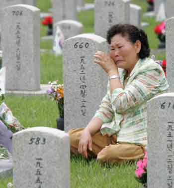 A South Korean woman cries at the gravestone of her uncle, who died during the 1950-1953 Korean War, at the national cemetery in Seoul June 6, 2005. South Koreans commemorated fallen patriots on Monday for the country's 50th Memorial Day. [Reuters]
