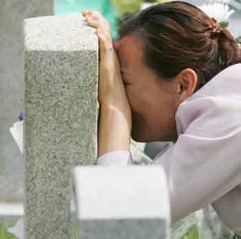 A South Korean woman cries at the gravestone of her brother who died in 1970 during his military service at the national cemetery in Seoul June 6, 2005. South Koreans commemorated fallen patriots on Monday for the country's 50th Memorial Day. [Reuters]