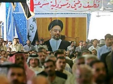 A poster of Shi'ite cleric and leader of the Supreme Council of the Islamic Revolution in Iraq (SCIRI) Abdul Aziz al-Hakim hangs over a Badr organization meeting in Baghdad June 8, 2005. The Badr Brigade was the military wing of the SCIRI but the group now performs social and political functions, the party said. Iraqi President Jalal Talabani today voiced his support for the Badr Brigade, which Sunni Arabs say is involved in killing members of their group. Photo by Ali Jasim/Reuters 