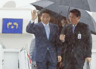 South Korean President Roh Moo-hyun (L) waves upon arrival amid a heavy downpour at Andrews Air Force Base outside Washington, June 9, 2005. Roh will meet U.S. President George W. Bush in Washington on Friday at a time when the two allies are cautiously weighing signs that North Korea could end a year-long boycott of six-country diplomatic talks on its nuclear ambitions. REUTERS