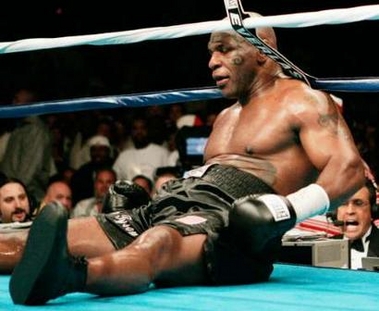 Mike Tyson sits on the canvas at the end of round six after Ireland's Kevin McBride pushed him to the mat during their heavyweight boxing fight at MCI Center in Washington June 11, 2005.