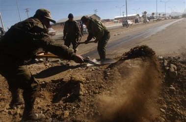 Boivian police officers use shovels to clear a blocked road in El Alto, Bolivia on Saturday, June 11, 2005. 