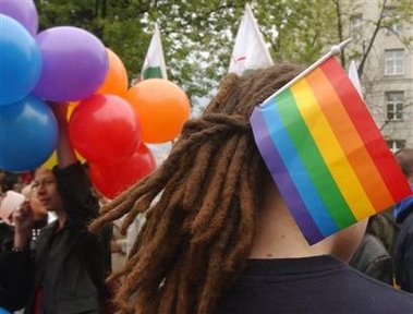 Gay rights supporter wears a multicolor flag during a gay parade in Warsaw, Poland, Saturday, June 11, 2005. More than 2,000 gay-rights supporters took to the streets of Warsaw Saturday in defiance of the city's conservative mayor, who banned the gathering for a second straight year. Gays, lesbians and their supporters carrying banners with slogans including 'A gay is not a pedophile' and 'Law and justice for all' rallied near parliament and marched to the Stalinist landmark Palace of Culture. (AP