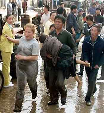 A man carries a child as other residents rush to rescue the children stranded in water in a primary school hit by a flash flood in Shalan town in Ning'an city, northeast China's Heilongjiang province Friday, June 10, 2005.