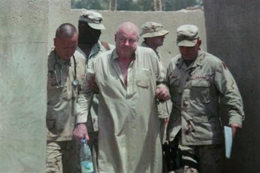 Photo issued by Australia's counterterrorism chief Nick Warner, showing former Australian hostage Douglas Wood, centre, as he is escorted by US military after he was freed in Baghdad, Iraq, Wednesday June 15, 2005. 