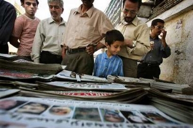 Iranians look at newspapers reporting on election results in Tehran June 19, 2005. 