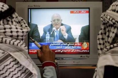 Palestinians follow the news on the summit of Palestinian President Mahmoud Abbas with the Israeli Prime Minister Ariel Sharon, at an electronic shop in the West Bank city of Hebron June 21, 2005. 