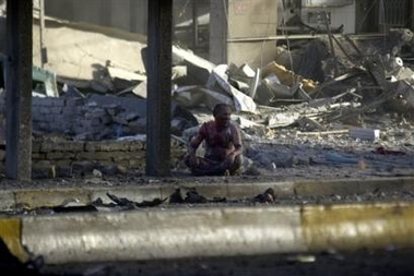 A injured man sits alone in the rubble at the site of explosions in Baghdad, Iraq Thursday, June 23, 2005. At least two car bombs exploded just after dawn Thursday in Baghdad's middle-class Karada area, a central shopping district.