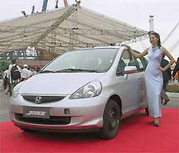 A model poses next to a Honda Jazz during a ceremony to see off the first shipment of 150 of the cars at the southern port of Guangzhou, China, as the Japanese carmaker Honda began exporting Chinese-made Jazz compacts to Europe. (AP