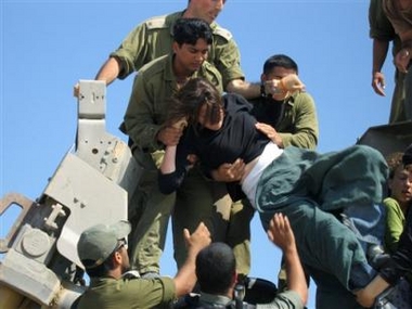 Israeli soldiers scuffle with a Jewish settler atop an Israeli army bulldozer on its way to demolish uninhabited former Egyptian resort homes outside the Jewish settlement of Shirat Hayam in the southern Gaza Strip, Sunday June 26, 2005. 