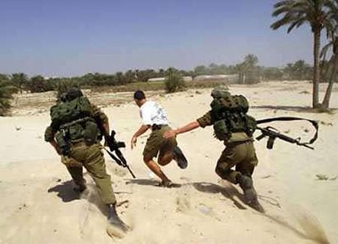 A Jewish settler is chased by Israeli soldiers near the Shirat Hayam settlement in the Gush Katif settlement bloc on June 26, 2005. 
