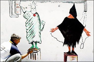 Iraqi artist Salah Edine Sallat puts the final touches to a wall painting based on the US Statue of Liberty and a widely published photograph of an abused detainee at the Abu Ghraib prison in Baghdad. 