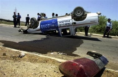 Iraqi police gather around an overturned police truck after unidentified gunmen opened fire from another vehicle killing one and injuring at least two others north of Baghdad, Iraq, Tuesday June 28, 2005. (AP