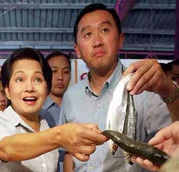Philippine Agriculture Secretary Arthur Yap (R) holds a fish beside President Gloria Macapagal Arroyo during a visit to a seafood market in Manila in this undated file photo. 
