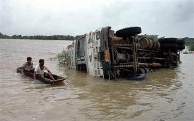 Villagers pass by an overturned truck in floodwaters at Umareth, about 85 kilometers (53 miles) east of Ahmadabad, India, Sunday, July 3, 2005.