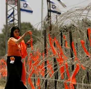 A Jewish settler girl hangs orange ribbons, the color of the anti-disengagement movement, on razorwire outside the military base near Kibbutz Ein Hashlosha, just outside the Gaza Strip, Monday, July 4, 2005. 