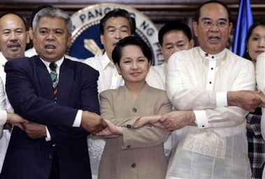 Philippine President Gloria Macapagal Arroyo, center, link arms with retired police officer Nestor Gualberto, right, and other active and retired police and military officers to show their support during their meeting at Malacanang palace in Manila on Monday July 4, 2005. 