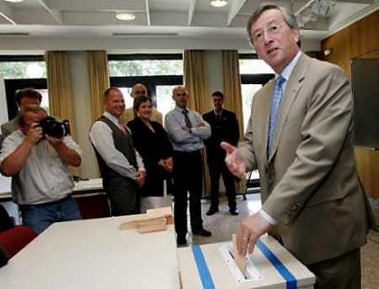 Luxembourg Prime Minister Jean-Claude Juncker (R) gestures as he casts his vote during a referendum on the European Union constitution at the Capellen Cultural Center in Luxembourg July 10, 2005.