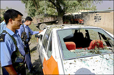 Iraqi police inspect the wreckage of a car that was destroyed at the site where a suicide bomber detonated his booby-trapped car outside Kirkuk's municipal offices, in northern Iraq.