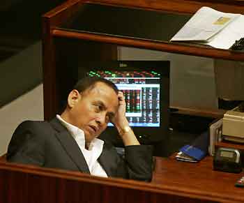 A Filipino floor trader monitors share prices at the Philippine Stock Exchange in Manila's Makati financial district July 13, 2005. Moody's Investors Service said on Wednesday it had cut its sovereign outlook on the Philippines because crucial reforms to cut the country's budget deficit had been thrown into doubt by a political crisis. [Reuters]
