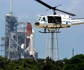 A security helicopter flies near the space shuttle Discovery on Pad 39B after launch was delayed at the Kennedy Space Center in Cape Canaveral, Florida, July 13, 2005. [Reuters]