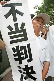 China's 68-year-old Wang Jinhua holds a banner after a legal judgement in front of the Tokyo High Court in Tokyo July 19, 2005.