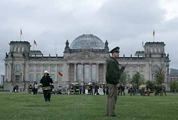 German police and firemen attend the scene next to the wreckage of a small aircraft following a crash in front of the Reichstag in Berlin late July 22, 2005. A light aircraft crashed onto the lawn in front of the Reichstag building that houses the German lower house of parliament in central Berlin on Friday, police said. It was a single-engined aircraft, the Berlin fire brigade said. According to a Reuters witness, the plane was almost completely burnt out.