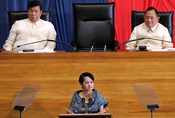 Philippine President Gloria Macapagal Arroyo (C) addresses the 13th Congress of the Philippines joint session at the House of Representatives in Manila July 25, 2005, as Senate President Franklin Drillon (L) and House of Representative speaker Jose de Venecia look on. Arroyo, facing an impeachment motion in Congress, said in a policy speech on Monday she was focused on reforms to raise revenues, cut debt and overhaul the country's political system. 