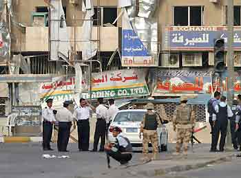 Iraqi police and soldiers stand guard outside a central Baghdad hotel after it was attacked by a suicide car bomber July 25, 2005.
