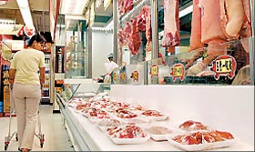A woman walks past a display of fresh pork at a supermarket in Hong Kong yesterday.?Hong Kong is on the alert after a mystery disease killed 19 in Southwest China, with the city抯 two main supermarket chains suspending sales of frozen pork from Sichuan.
