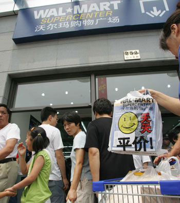 Shoppers stand before a newly-opened Wal-Mart store in the Pudong New Area of Shanghai July 28, 2005. It's the world's largest retailer's first shopping mall in Shanghai. Wal-Mart plans to increase its China outlets to 90 by the end of 2006. [newsphoto
