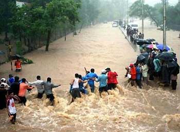 People hold on to a rope to cross a street after heavy rains in Bombay, India, Wednesday, July 27, 2005. The strongest rains ever recorded in India shut down the financial hub Bombay on Wednesday, snapping communication lines, closing airports and marooning thousands of people. Authorities said Wednesday they had recovered at least 200 bodies in western India. (AP 