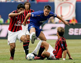 Chelsea's John Terry (C) kicks the ball between AC Milan's Gennaro Gattuso (L) and Alberto Gilardino during first half play of their friendly soccer match in East Rutherford July 31, 2005.