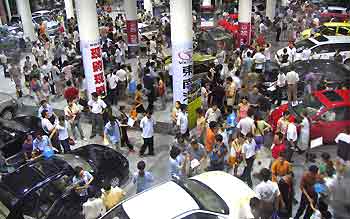 People crowd around a nighttime automobile fair in Ningbo, a coastal city in East China's Zhejiang Province, July 12, 2005. [newsphoto]