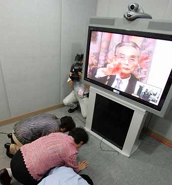 (L-R) South Koreans Chung Yong-ae, Chung Yong-im and Chung In-gul bow to their North Korean brother Chung Byong-yun on a TV screen at a video family reunion session in Seoul August 15, 2005. The cable linking Seoul and Pyongyang is used for the first video reunions of families torn apart by the 1950-53 Korean War. [Reuters]