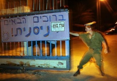 An Israeli army soldier closes the gate of the entrance to the nothern Gaza Strip Jewish settlement of Nissanit shortly after midnight Monday Aug. 15, 2005.