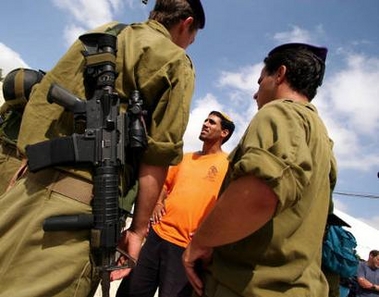 An Israeli settler dressed in an orange T-shirt speaks to two Israeli soldiers in the Morag settlement in the Gush Katif area of the Gaza Strip August 16, 2005. 