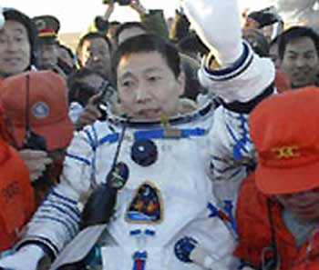 Yang Liwei, China's first space man, waves to the recovery teams after walking out of the return capsule of the Shenzhou V spaceship Thursday morning, October 16. [Xinhua]