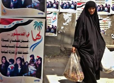 An Iraqi woman walks next to posters promoting women's rights in the new constitution, in the southern city of Basra, Iraq Monday, Aug. 22, 2005. 