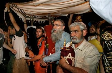 A settler and two of Netazarim's Rabbis, center and right, evacuated earlier from the Jewish Gaza settlement of Netzarim carry the Torah scrolls removed from the settlements's synagogue during a protest march in front of Jerusalem's Western Wall late Monday Aug. 22, 2005. 