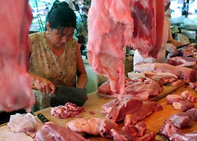 A vendor prepares pork at a market in Shanghai yesterday. China�s far south is on high alert since one person was killed and three infected by a pig-borne disease that had left nearly 40 dead in the southwest. The latest person killed by the disease, caused by the Streptococcus suis bacterium, had handled infected pork, Xinhua news agency said on Tuesday. The three other victims, all butchers, also likely had contact with infected meat.
