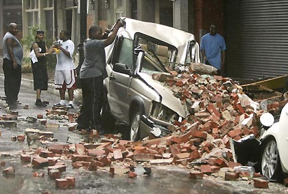 People look at a car crushed after a side of a building collapsed in downtown New Orleans, after Hurricane Katrina hit, August 29, 2005.