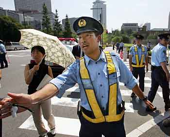 A policeman yells at people to stay back outside Japanese Prime Minister Junichiro Koziumi's official residence in Tokyo after a woman attempted suicide outside its gate August 30, 2005.