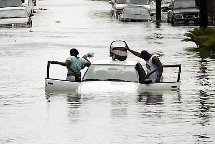 A man puts his baby on top of his car as he and a woman abandon their car after it started to float when Hurricane Katrina hit the Terme area of New Orleans August 29, 2005. The White House said Monday it was willing to use the government's emergency oil stockpile to help refiners hurt by Hurricane Katrina's rampage through the Gulf of Mexico, but that it was too early to decide if or how much crude should be released. The storm slammed into New Orleans on Monday with winds of 135 mph (216 kph), shutting 91 percent of the normal 1.5 million barrels per day of crude oil production in the Gulf Coast region.