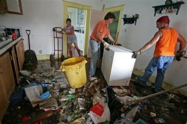 Patricia Runnels, left watches as Monty Ladner and Keith Wilkes, right remove a freezer from her home in Gulfport, Miss., on Sunday, Sept. 4, 2005. Runnels was attempting to clear as much of the debris caused by Hurricane Katrina in an attempt to save her floors. (AP